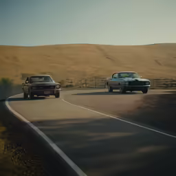 two classic cars driving on the road near hills