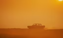 a car is driving through the sand during the sunset