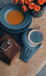 a phone, cup of liquid and flower arrangement on a table