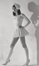 a woman in a short skirt is posing in front of a shadow