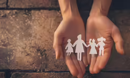 two hands holding some paper cutouts of people