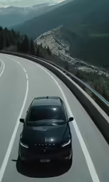 a black car driving on the highway towards trees and mountains