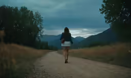 a woman walking alone down the road carrying a book