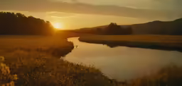 the sun setting over a grassy field with small river in the middle