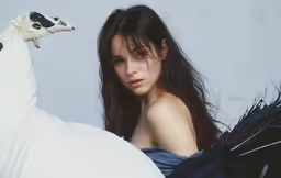 a girl wearing black dress laying on white pillow