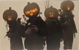 the group of men in pumpkin heads has carved orange letters on their faces
