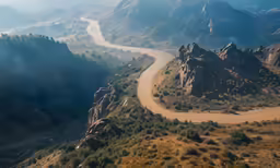 the highway is winding into the mountains, and the sky is blue