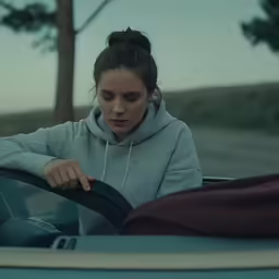 a girl in a car looks down on her hoodie