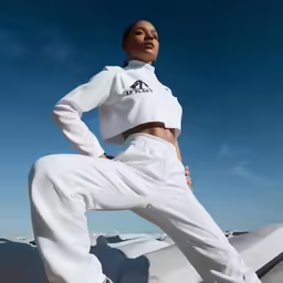 woman in white sports gear posing with her arms akar