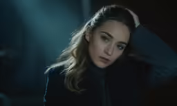 a woman in a black jacket holds her hair up