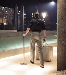 a man walking into a building at night with his luggage