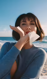 a woman is holding a paper in her hand while she holds it in front of her face