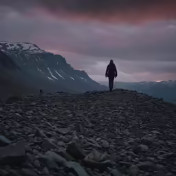 a man walking up a mountain at sunset