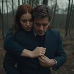 the man is embracing the woman in the forest