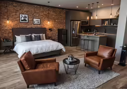 a living area with a bed, chair and kitchen