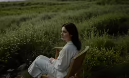 woman in white robe sitting on a wooden lawn chair