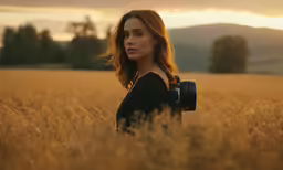 a woman standing in a field holding a camera