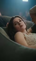 a couple laying on a sofa during a darkened room