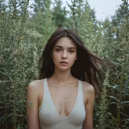 a girl posing in front of a field with tall grass