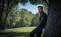 a man with his legs propped up against the side of a tree