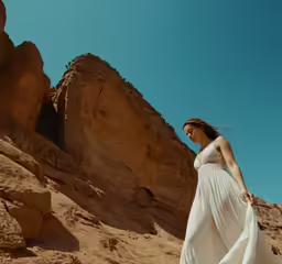 a woman walks through the desert in her long, flowing white dress