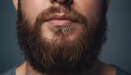 a man with a messy, freckled beard and a frown