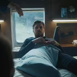 a man laying in bed in front of a window