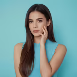 a young woman is wearing a blue shirt and standing in front of a blue background