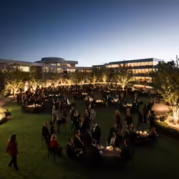 a group of people sitting on lawn with tables and chairs