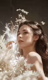 a woman wearing long hair and white gown surrounded by flowers