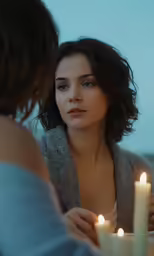 the woman holds a candles light near another woman