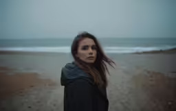 the woman is standing on the shore staring at the camera