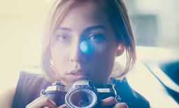 a woman is holding a camera in her hands
