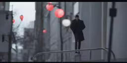 a person in the rain walking towards red lights