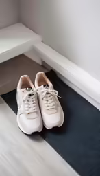 a pair of beige shoes on a mat near a white chair