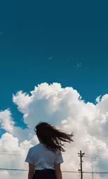 the rear view of a woman standing with long hair up to the sky