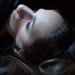 a woman laying on her side with a black jacket