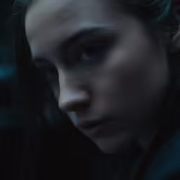 a close - up of a person in dark lighting looking down