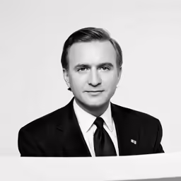 a man in suit and tie standing near some papers