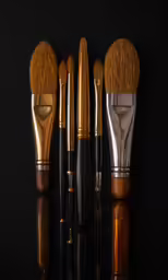 four types of makeup brushes lined up against a black background