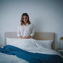 a woman is staring at the camera in a dark room with a bed