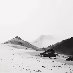 a snowy field surrounded by hills and trees