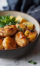 a brown bowl filled with food next to lemon wedges