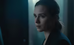 a woman wearing a black jacket looks away from the camera