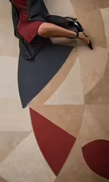 a woman wearing black dress and high heels sitting on floor