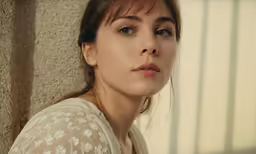 a close up photo of a woman with long hair and white blouse