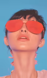 woman wearing red sunglasses over her eyes and a pink shirt