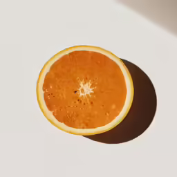 an orange half with the shadow of a human eye on a white surface
