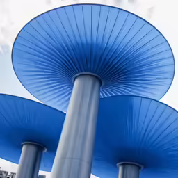three blue umbrellas are shown against a cloudy sky