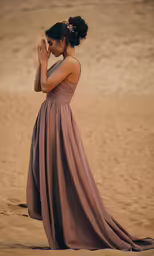 a woman in an elegant dress standing on the beach